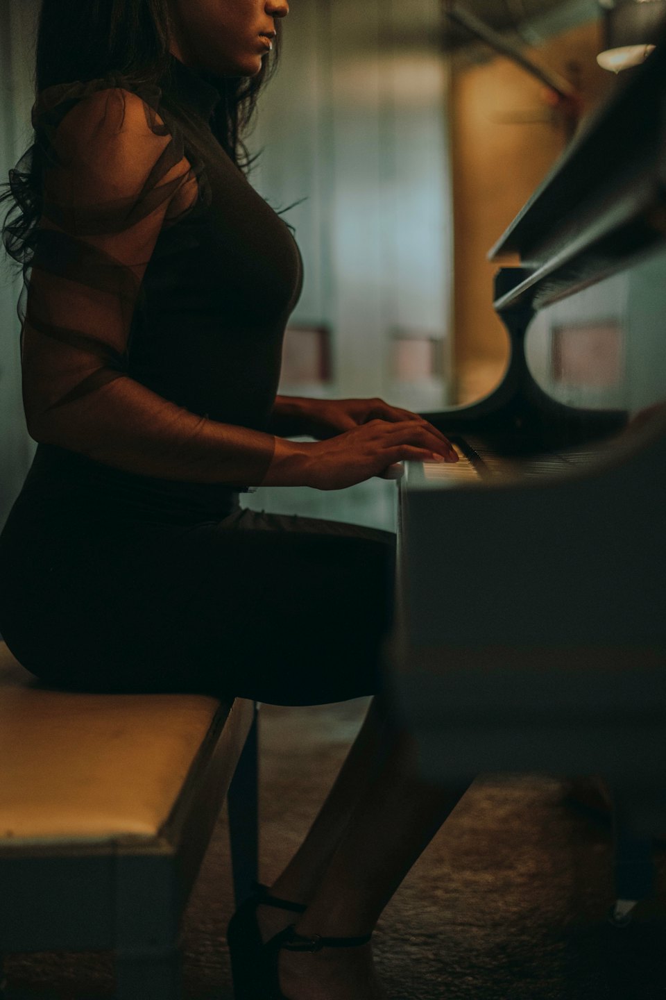 Woman in a black dress plays the grand piano.