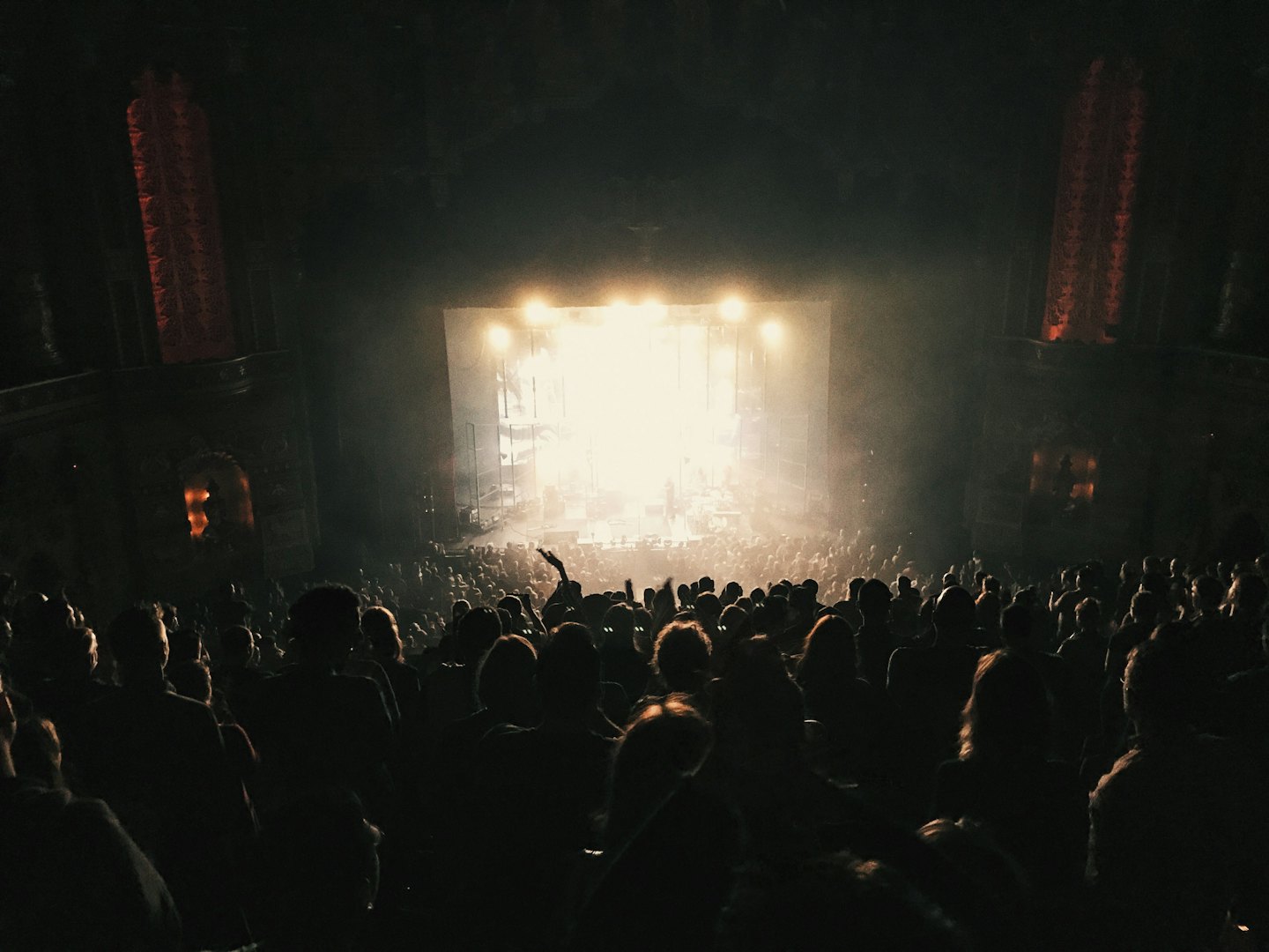 A crowd watches a live performance on an ornate indoor stage.